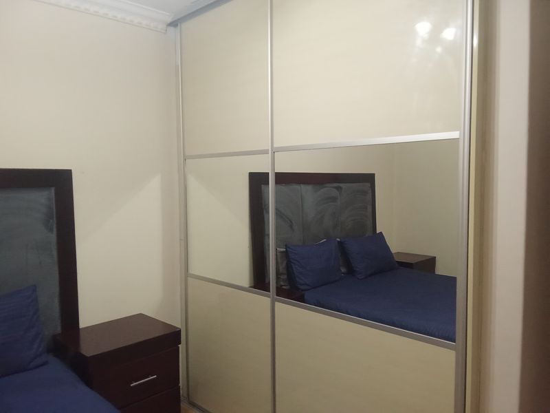 A bedroom featuring a large built-in sliding door wardrobe with mirrored panels and decorative ceiling cornice detailing.