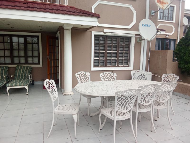 A covered outdoor patio area featuring tiled flooring, a structural column, and recessed lighting, providing a functional space for outdoor dining and relaxation.