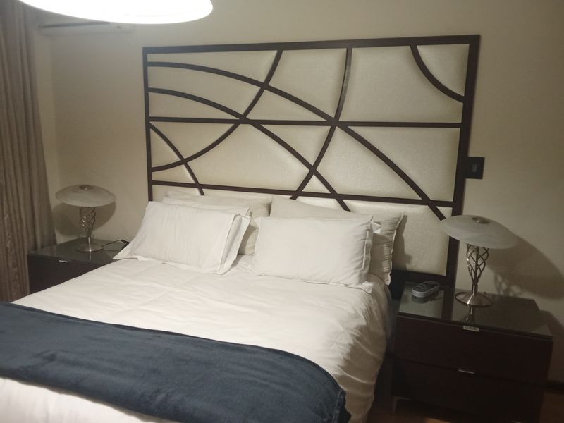 A well-maintained bedroom featuring a decorative built-in headboard and an integrated air conditioning unit.
