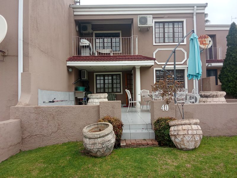 Rear view of the apartment featuring a ground floor patio, upper balcony, tiled flooring, and built-in exterior sink area.