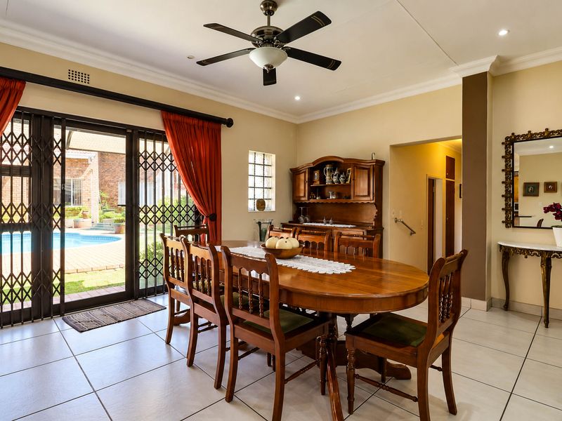 A well-maintained dining room featuring tiled floors, a ceiling fan, and large sliding glass doors providing direct access to the outdoor pool area.
