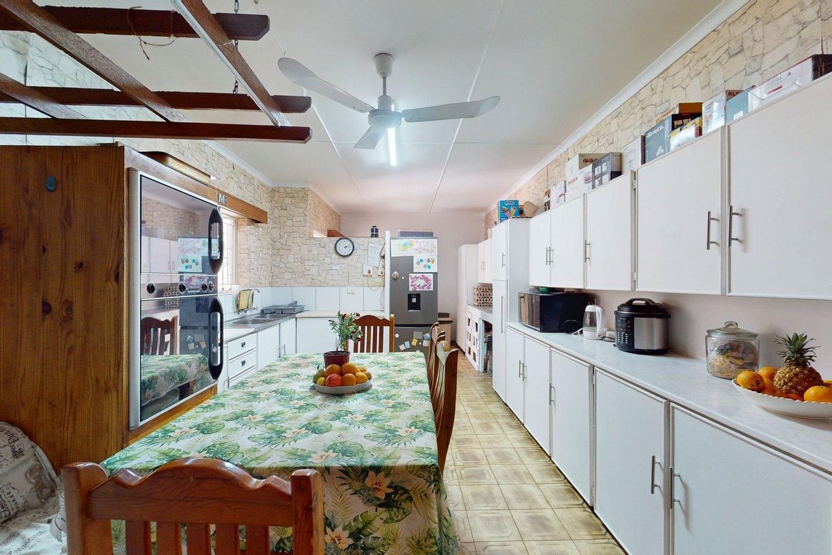 Spacious kitchen featuring extensive built-in cabinetry, a double oven, and tiled flooring, offering a functional layout with potential for modern updates.