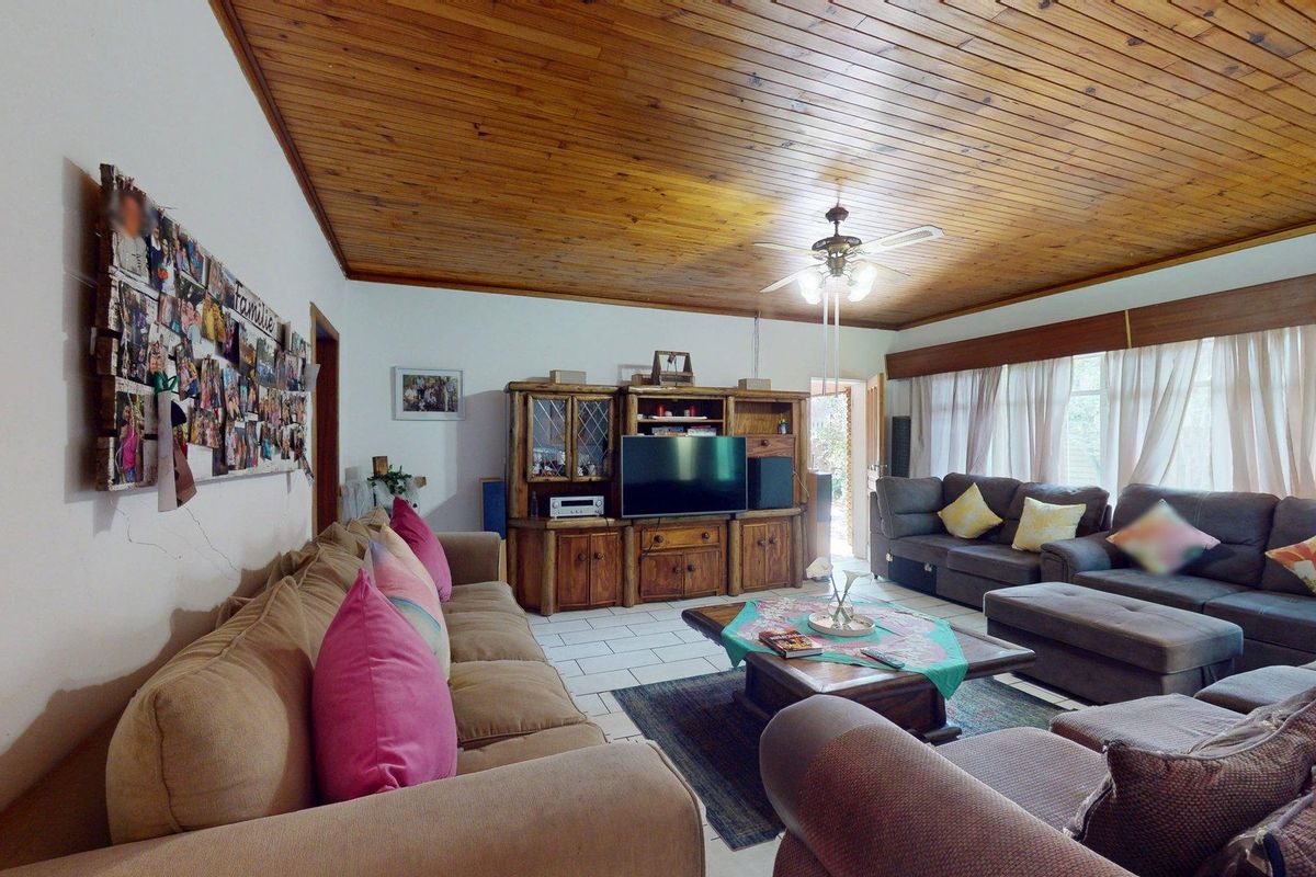Spacious living room featuring a warm timber tongue and groove ceiling, ceiling fan, and tiled flooring.