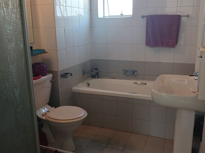 A dated bathroom featuring a bathtub, pedestal basin, toilet, and separate shower enclosure with tiled finishes throughout.