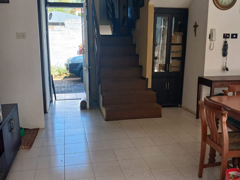 Entrance area featuring tiled flooring, a staircase with carpeted steps, and a built-in display cabinet, providing direct access to the exterior.