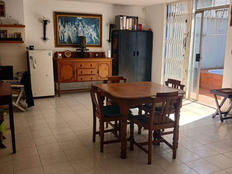 Open plan living and dining area featuring tiled flooring and direct access to an outdoor patio through a sliding glass door with security gate.