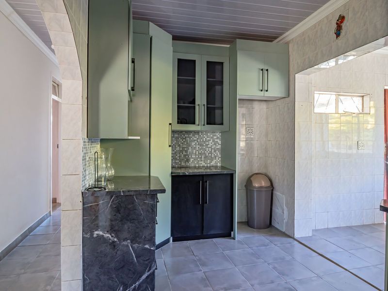A functional kitchen space featuring built-in cabinetry, stone countertops, and tiled finishes, offering a clean canvas for potential modern updates.