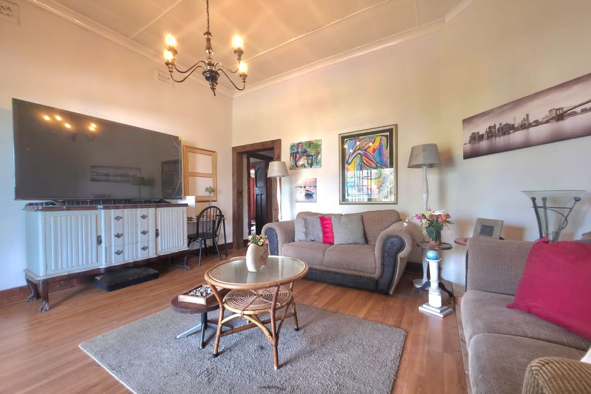 A spacious living room featuring laminate flooring, classic coved cornicing, and a central ceiling rose, offering a comfortable and traditional living environment.