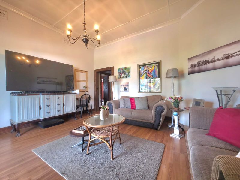 A spacious living room featuring laminate flooring, classic coved cornicing, and a central ceiling rose, offering a comfortable and traditional living environment.