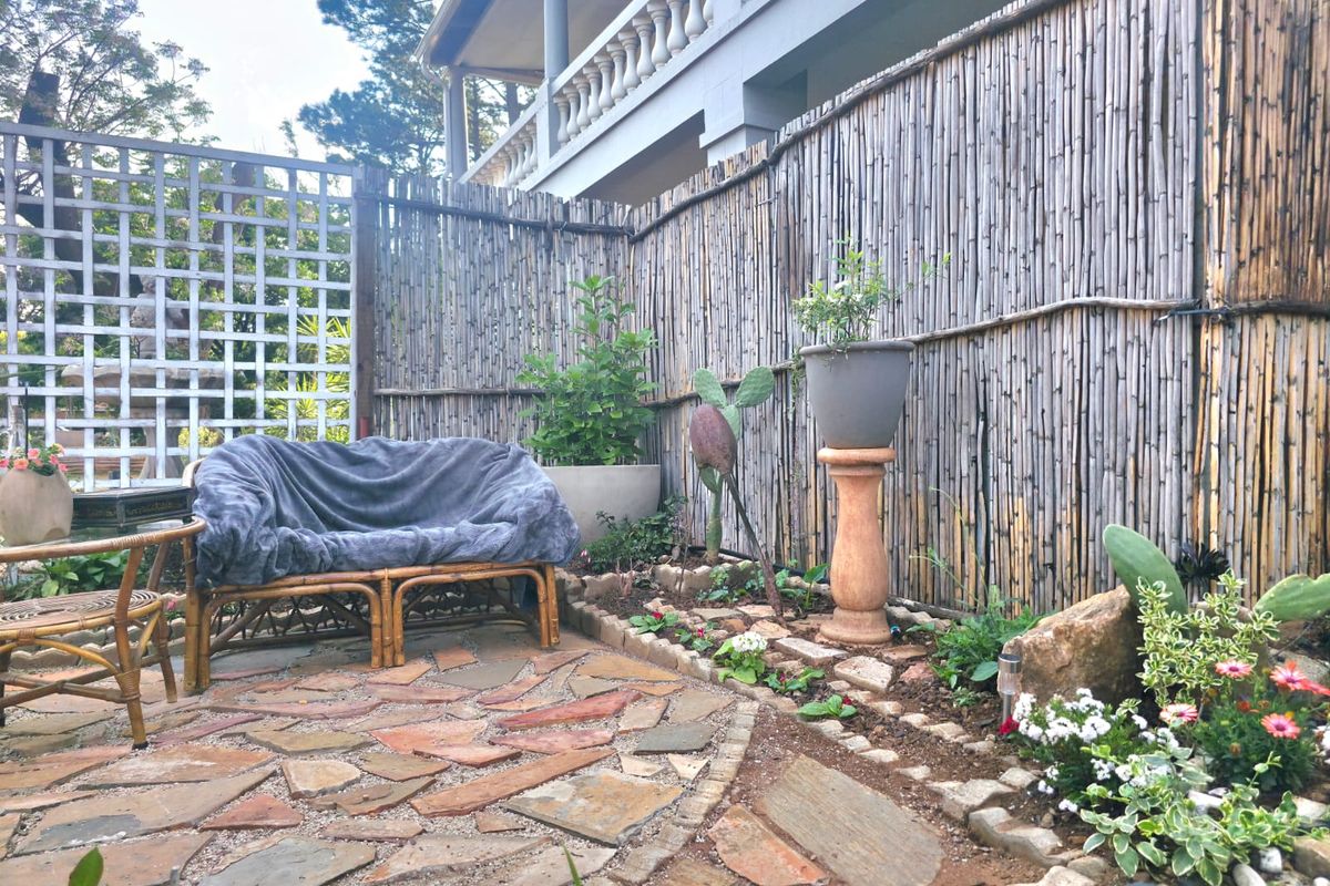 A private rear courtyard featuring natural stone paving, bamboo privacy fencing, and a decorative lattice screen.