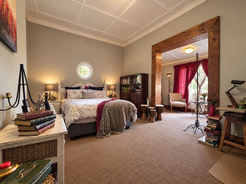 Spacious bedroom featuring a unique coffered ceiling, a circular accent window, and a large timber-framed opening leading to an adjoining sitting area.