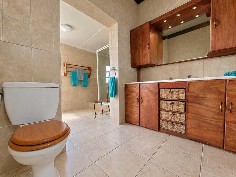 Spacious bathroom featuring a large wooden vanity with integrated mirror, ceramic tiling throughout, and a separate shower enclosure.