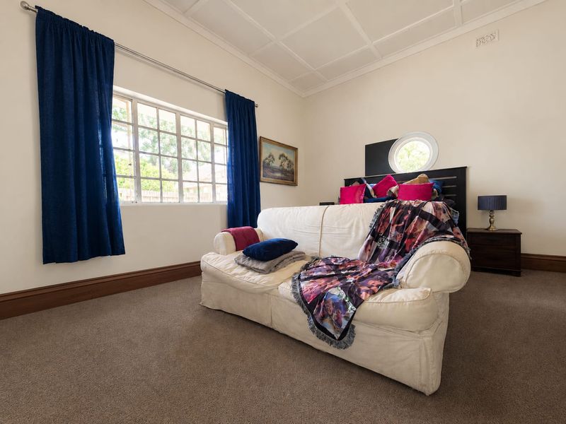Spacious bedroom featuring a unique circular window, grid-style window, and classic coffered ceiling detail, providing a bright and character-filled living space.