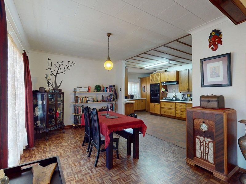 Open-plan living and dining area featuring parquet flooring, flowing into a functional kitchen with built-in wooden cabinetry and integrated appliances.