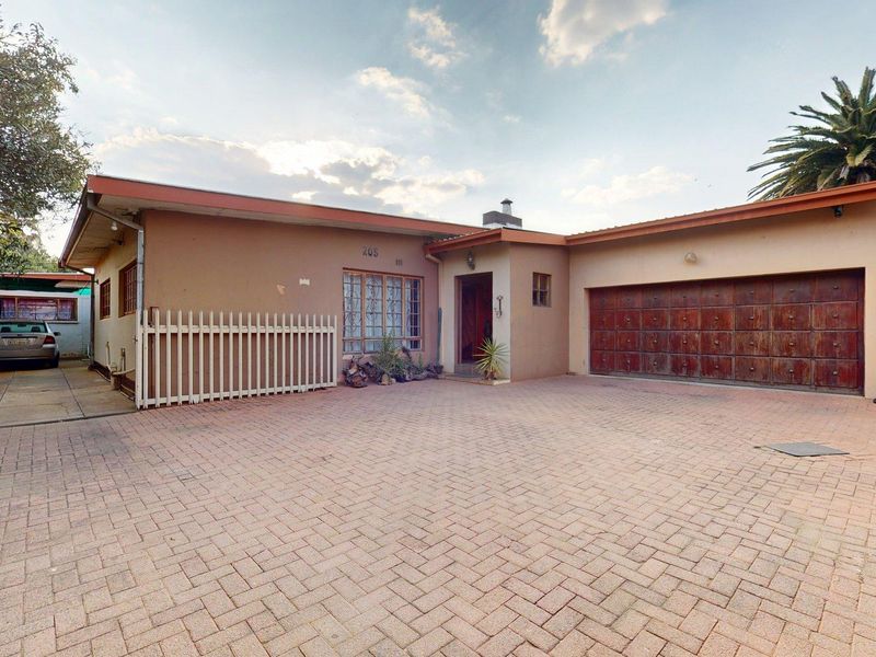 Front elevation of a single-story house featuring a paved driveway, integrated double garage with wooden doors, and a secure entrance.