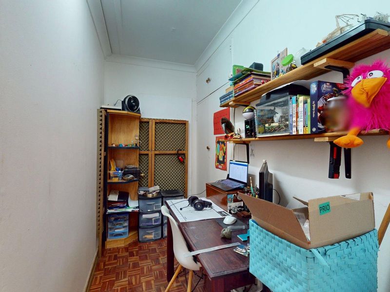 A compact home office space featuring parquet flooring and built-in shelving, offering a functional area for work or study.