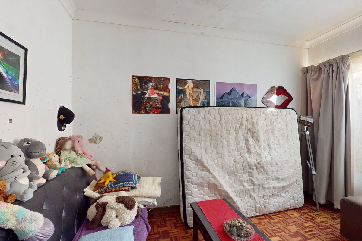 A bedroom featuring parquet flooring and wall surface damage, requiring cosmetic repairs and repainting to restore the space.