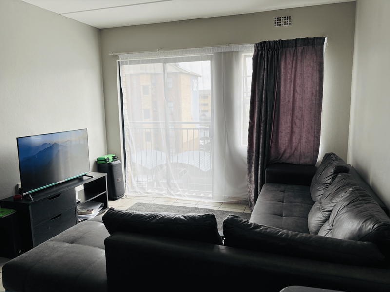 A living room featuring tiled flooring, a sliding glass door leading to a balcony, and a built-in ventilation grille.
