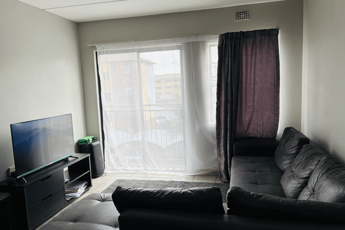 A living room featuring a sliding glass door that opens onto a balcony, providing natural light and access to outdoor space.