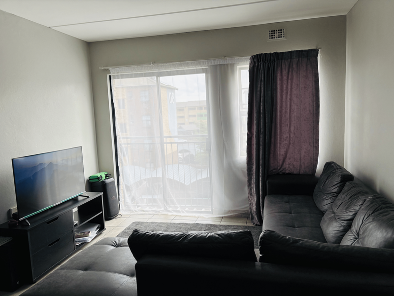 A living room featuring a sliding glass door that opens onto a balcony, providing natural light and access to outdoor space.