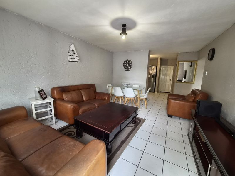 Open-plan living and dining area featuring tiled flooring and textured walls, offering a functional layout for daily living and entertaining.