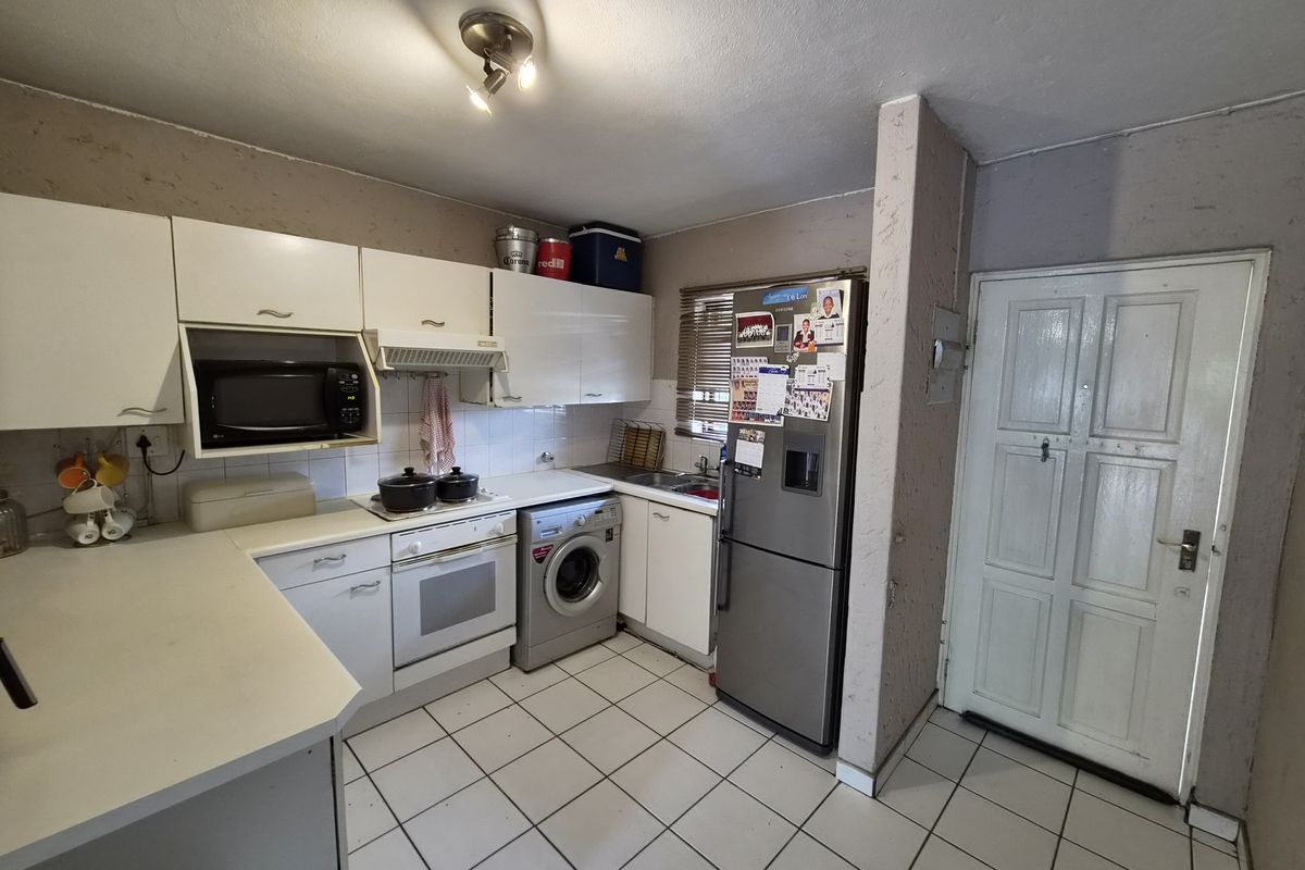A functional kitchen featuring white cabinetry, laminate countertops, built-in oven, and tiled flooring, offering a practical layout with direct access to the exterior.