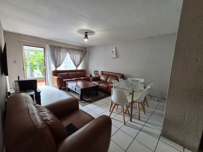 Open-plan living and dining area featuring tiled flooring, textured walls, and direct access to an outdoor balcony through a sliding glass door.