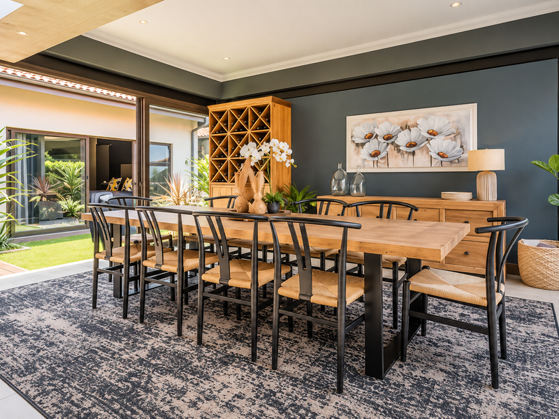 A modern, well-lit dining room featuring large sliding glass doors that open to an outdoor area, complemented by elegant dark accent walls.