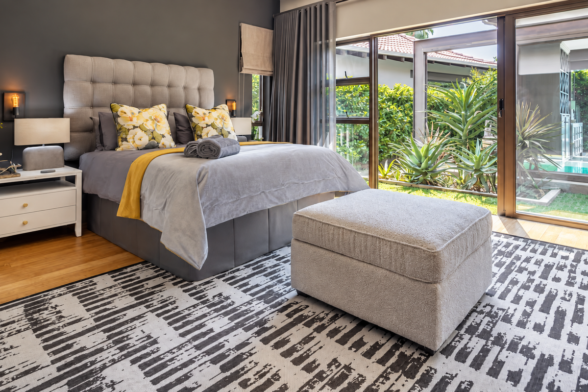 Modern bedroom featuring hardwood flooring and large sliding glass doors that provide direct access to the garden and pool area.