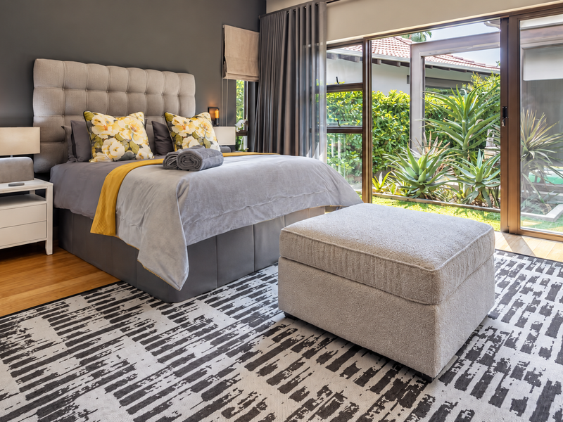 Modern bedroom featuring hardwood flooring and large sliding glass doors that provide direct access to the garden and pool area.