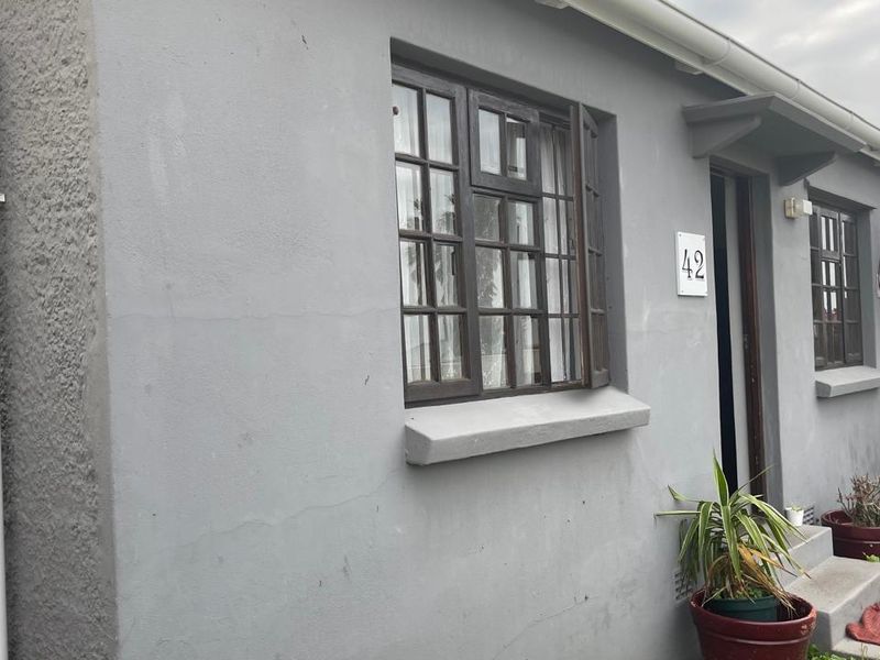 Front facade of a townhouse featuring plastered walls, timber-framed windows, and concrete entrance steps.