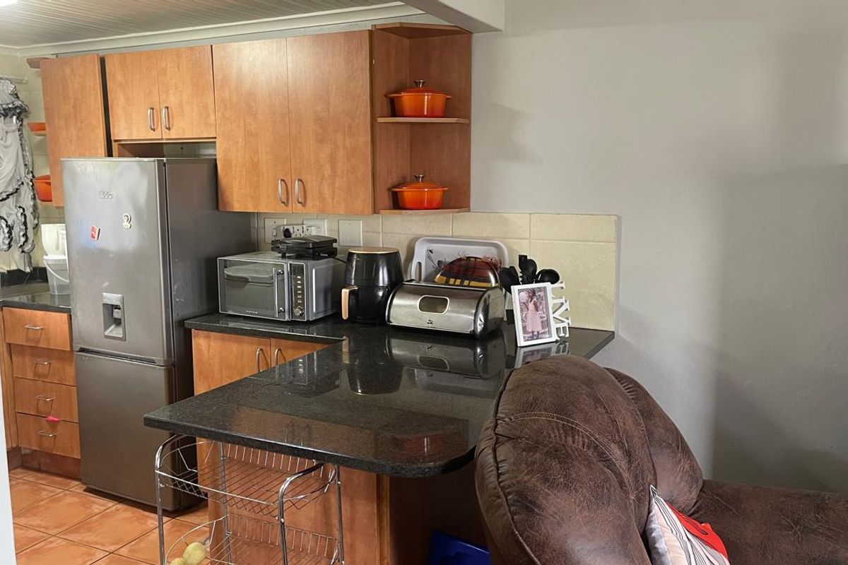 A functional kitchen featuring laminate cabinetry, granite countertops, and a tiled backsplash, offering a practical layout for daily meal preparation.