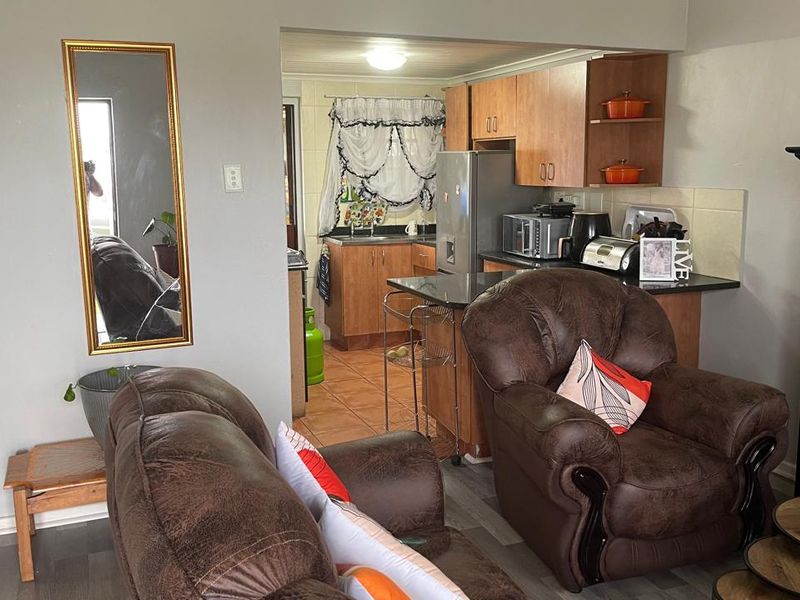 Open plan living area featuring a functional kitchen with wood-finish cabinetry, granite countertops, and a seamless transition between the kitchen and lounge space.