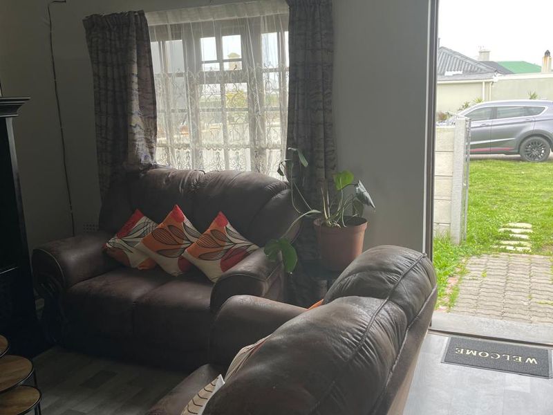 A living room area featuring laminate flooring and direct access to the exterior through a doorway.
