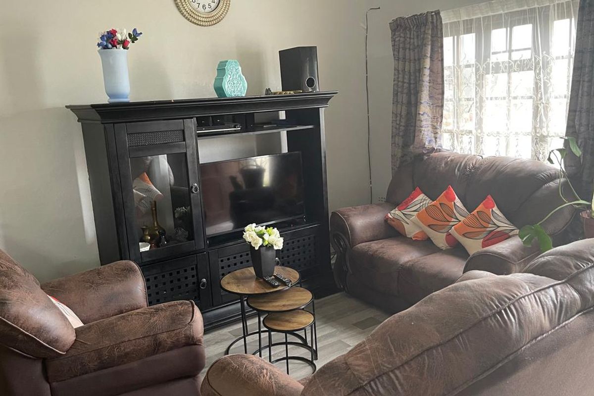 A comfortable living room featuring laminate flooring and natural light from the window, providing a functional space for relaxation.