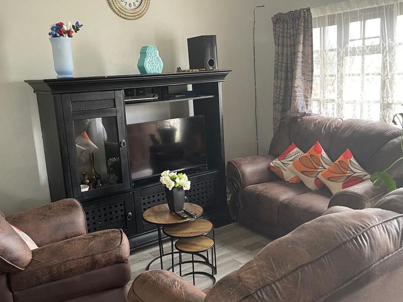 A comfortable living room featuring laminate flooring and natural light from the window, providing a functional space for relaxation.