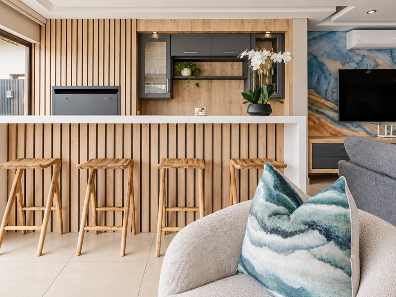 A modern, well-appointed built-in bar area featuring timber slat detailing, sleek cabinetry, and integrated lighting, seamlessly integrated into the living space.