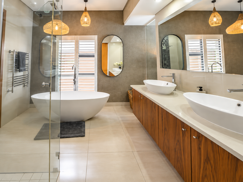 Modern bathroom featuring a freestanding bathtub, double vanity with vessel sinks, glass-enclosed shower, and high-quality finishes throughout.