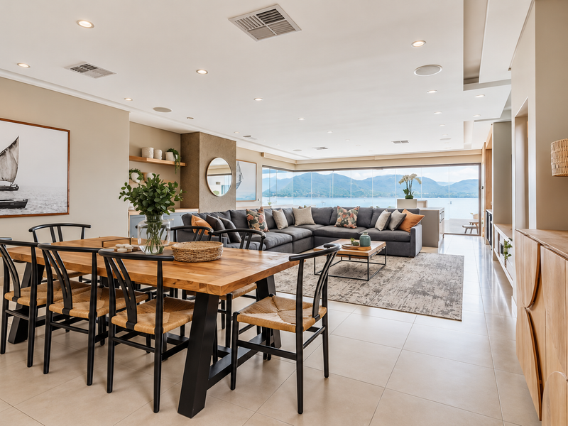 Spacious open-plan living and dining area featuring tiled floors, recessed lighting, and expansive glass doors offering panoramic water and mountain views.