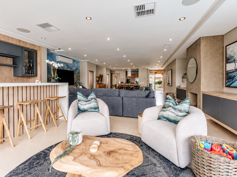 Spacious open-plan living area featuring a modern built-in bar, recessed lighting, ducted air conditioning, and seamless flow between the lounge and kitchen spaces.