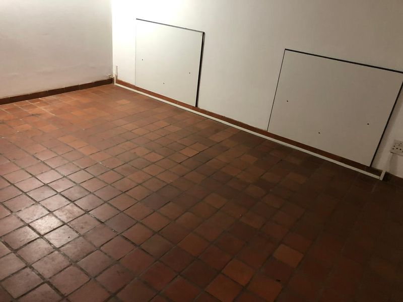 An empty room featuring traditional terracotta tile flooring and built-in wall access panels, presenting a blank canvas for renovation.