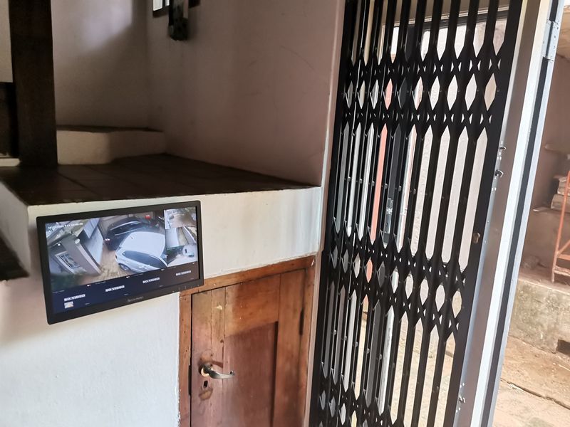Entryway featuring a security gate, built-in wooden cabinetry, and a wall-mounted CCTV security monitor.
