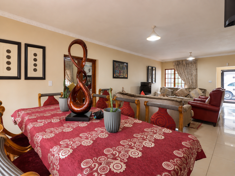 Spacious open-plan living and dining area featuring neutral walls, tiled flooring, and decorative coving, providing a versatile layout for family living.