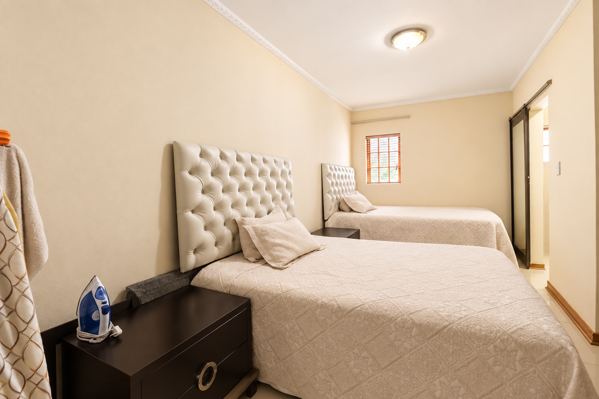 A well-maintained bedroom featuring neutral walls, ceiling cornicing, a sliding door, and a window with wooden blinds.