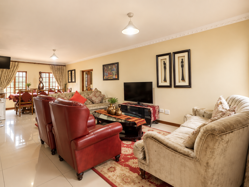 Spacious open-plan living and dining area featuring tiled flooring, crown molding, and abundant natural light through classic french doors.