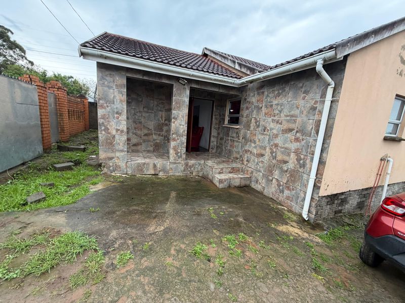 Rear exterior view of the property featuring a tiled facade, concrete patio area, and standard roof structure.