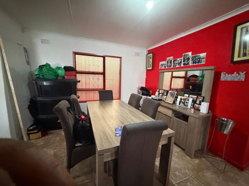 A dining room featuring tiled flooring, cove cornicing, and a window with fitted blinds, providing a functional space for family meals.