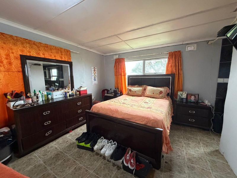 A bedroom featuring tiled flooring and a tiled ceiling, requiring cosmetic updates to the wall finishes and ceiling to improve the overall aesthetic.