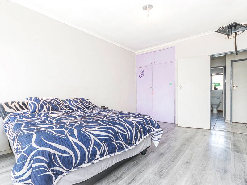 A bedroom featuring laminate flooring, built-in cupboards, and direct access to an adjoining bathroom.