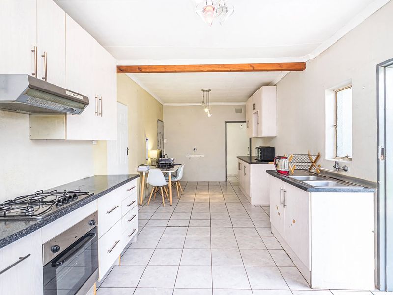 A functional kitchen featuring tiled flooring, laminate cabinetry, a gas hob, built-in oven, and a double sink with direct access to an outdoor area.